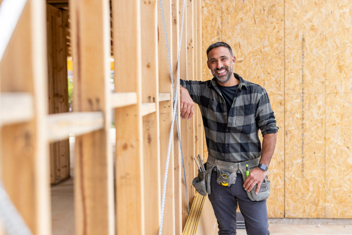 Adam Dovile keaning against timber frame on a building site while filiming the 2023 TV campaign.